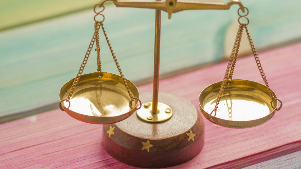 A small gold balance scale on a wooden table
