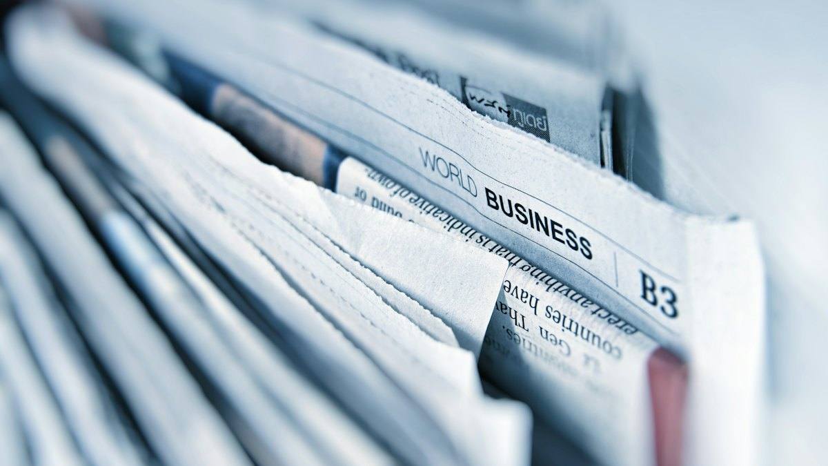A stack of newspapers open at the business section