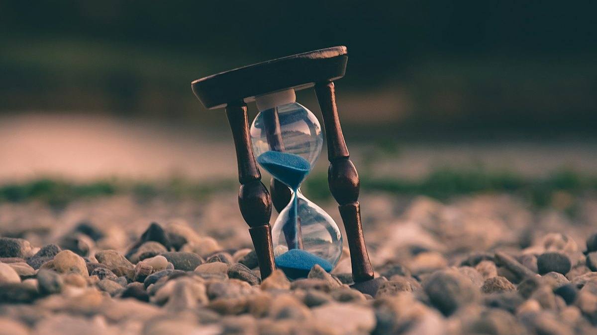 An hourglass on pebbles with sand running through