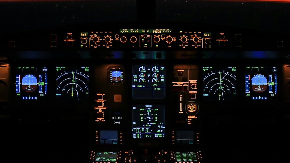 An airliner cockpit at night with its instruments glowing